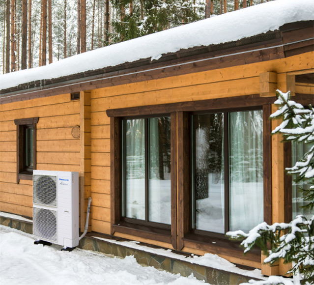 Dom pokryty śniegiem z zamontowaną pompą ciepła Panasonic